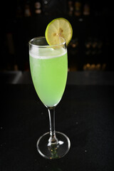 bartender special cold green lime cocktail or mocktail fruit juice with lime in tall glass goblet on black background luxury hotel pub iced beverage menu