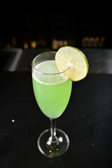 bartender special cold green lime cocktail or mocktail fruit juice with lime in tall glass goblet on black background luxury hotel pub iced beverage menu