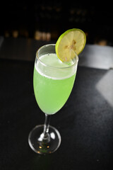 bartender special cold green lime cocktail or mocktail fruit juice with lime in tall glass goblet on black background luxury hotel pub iced beverage menu