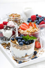 sweet desserts with fresh berries in glasses on white wooden tray, top view closeup