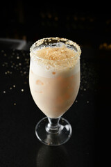 bartender special cold peanut or almond cocktail mocktail with fresh coconut milkshake juice in tall glass goblet on black background luxury hotel pub iced beverage menu