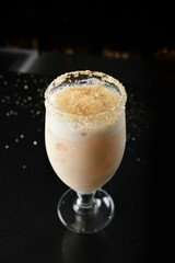 bartender special cold peanut or almond cocktail mocktail with fresh coconut milkshake juice in tall glass goblet on black background luxury hotel pub iced beverage menu