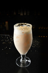 bartender special cold peanut or almond cocktail mocktail with fresh coconut milkshake juice in tall glass goblet on black background luxury hotel pub iced beverage menu
