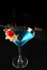 bartender special cold blue island cocktail or mocktail fruit juice with apple and cherry in tall glass goblet on black background luxury hotel pub iced beverage menu