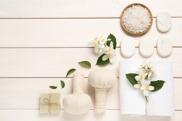 Flat lay composition with spa stones and beautiful jasmine flowers on white wooden table, space for text