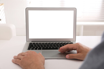 Man with modern laptop at white table indoors, closeup. Space for design
