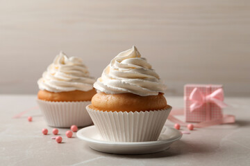 Delicious cupcakes decorated with cream on light grey table