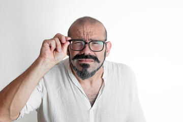 Caucasian man with moustache and glasses with vision impairment, dressed in white on white background isolated