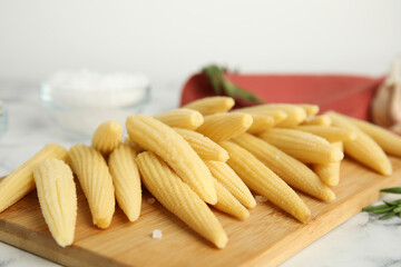 Delicious fresh baby corn cobs on wooden board, closeup