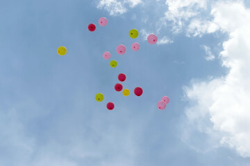 Many colorful balloons are flying in the sky against the background of clouds