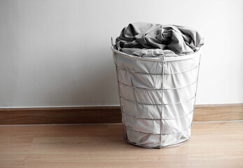 Modern basket with dirty laundry on floor