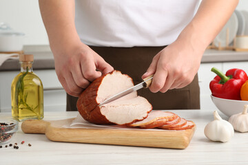 Man cutting delicious ham at white wooden table indoors, closeup