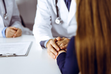 Unknown man-doctor reassuring his female patient, close-up. Two physicians consulting and giving...