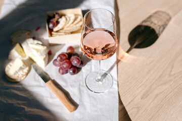 A glass of rose wine with appetizers on a white background.