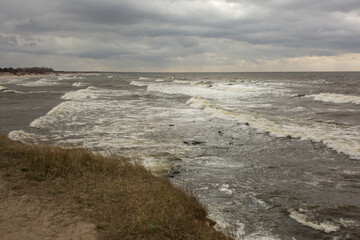 View from the cliff to the raging sea. Cloudy autumn weather on the shore, strong wind