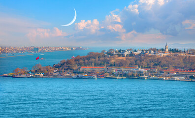 Famous historical peninsula with  Topkapi Palace, crescent moon in the background - Water trail foaming behind a passenger ferry boat in Bosphorus  - Istanbul, Turkey
