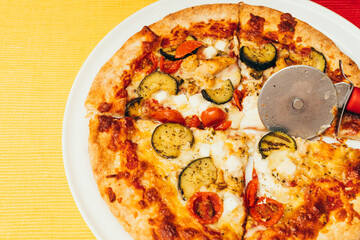 chicken and cherry tomato and vegetable pizza with sourdough and crispy golden crust on a white plate and yellow tablecloth with space for copy and paste text.