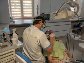 Dental clinic. Dentist treats teeth of a young adult woman.