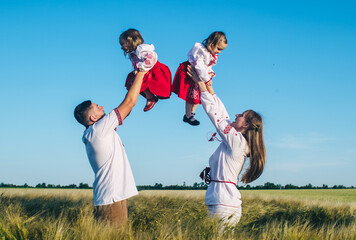 A family in a poppy field dressed in a national Slavic costume. Mom, dad and twin girls in...