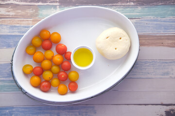 cherry tomato, cheese and olive oil on table 