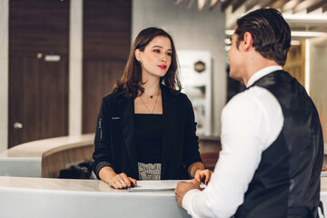 Young handsome businessman talking and check in register information with woman receptionist worker...