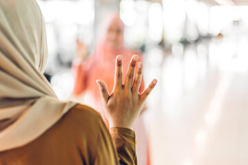Two young friend beauty islamic asian arabic muslim woman wearing a hijab enjoying and having fun talking together waving hi and saying hello in the shop at fashion store