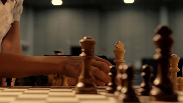Children's hands move chess pieces on the chessboard 