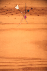 Wooden table background with colored heart-headed pins. With space for copy and place for text