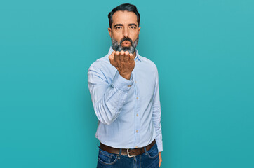 Middle aged man with beard wearing business shirt looking at the camera blowing a kiss with hand on air being lovely and sexy. love expression.