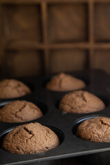 Homemade chocolate cupcakes in a cooking mold, standing on a wooden table.
