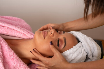 Obraz na płótnie Canvas Woman hands provides professional beauty face treatment on clean young woman face in lying position in beauty studio