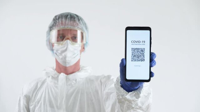 Doctor in Protective Suit Showing a Certificate of Vaccination on a Mobile Phone. - Powered by Adobe