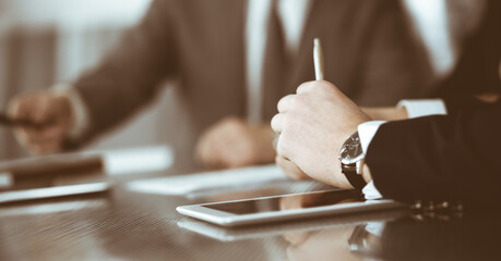 Unknown businessmen and woman sitting, working and discussing questions at meeting in modern office, close-up