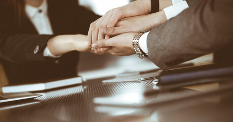 Unknown business people group joining hands in modern office. Businessmen and women making circle with their hands as a team, close-up