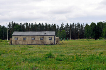 A military camouflage tent stands on the lawn