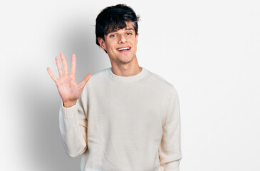 Naklejka premium Handsome hipster young man wearing casual winter sweater showing and pointing up with fingers number five while smiling confident and happy.