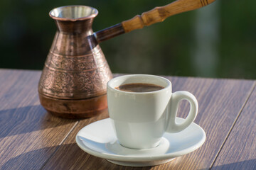 A cup of freshly brewed expresso coffee is on the table. Natural coffee made in a Turk.