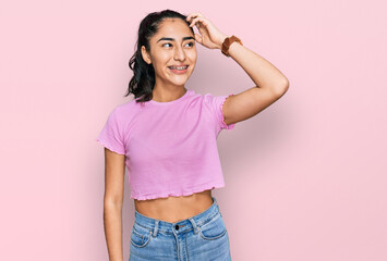 Hispanic teenager girl with dental braces wearing casual clothes smiling confident touching hair with hand up gesture, posing attractive and fashionable - obrazy, fototapety, plakaty