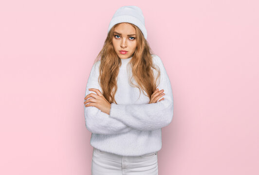 Young caucasian girl wearing wool sweater and winter cap skeptic and nervous, disapproving expression on face with crossed arms. negative person.
