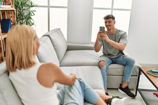 Man making photo to his girlfriend using smartphone at home.