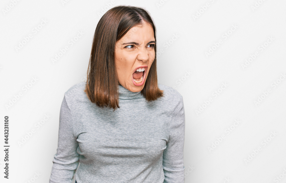 Poster young beautiful woman wearing casual turtleneck sweater angry and mad screaming frustrated and furio