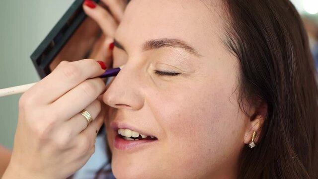 women do make-up, paint the eyelids on the eyes with a makeup brush. 