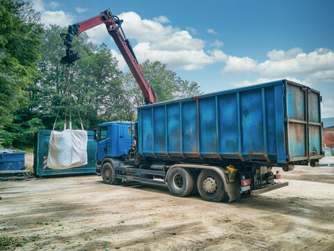 Crane truck with garbage bag on a recycling yard.