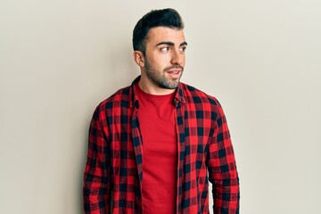 Young hispanic man wearing casual clothes looking to side, relax profile pose with natural face and confident smile.