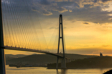 Fototapeta na wymiar Russian bridge across the Eastern Bosphorus Strait in Vladivostok. Russian bridge to the Russky island against the background of a bright dawn.