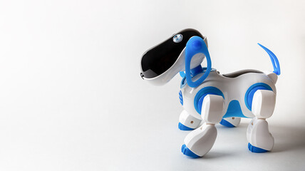 Blue and white robot dog with remote control on a white paper background closeup with copy space.