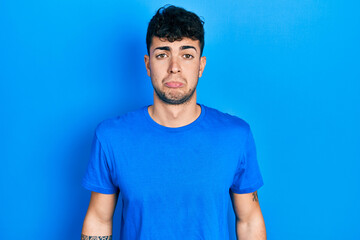 Young hispanic man wearing casual blue t shirt depressed and worry for distress, crying angry and afraid. sad expression.