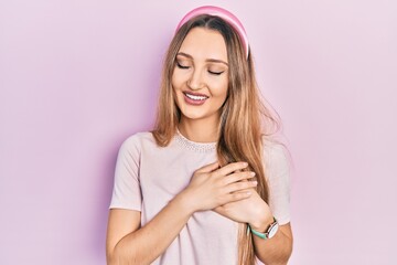 Young blonde girl wearing casual clothes smiling with hands on chest with closed eyes and grateful gesture on face. health concept.