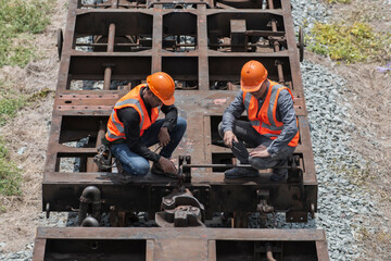 worker on a site. top view two service engineer on the bogie and checking joint.
