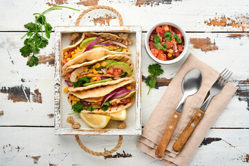 Mexican tacos with grilled chicken, avocado, corn kernels, tomato, onion, cilantro and salsa old white wooden table. Traditional Mexican and Latin american street food. Top view.